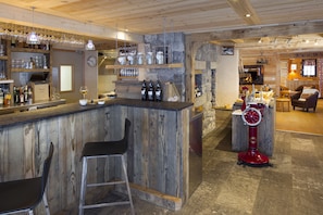 Un coin bar au style rustique, avec un comptoir en bois, des tabourets et une machine à crème glacée rouge.