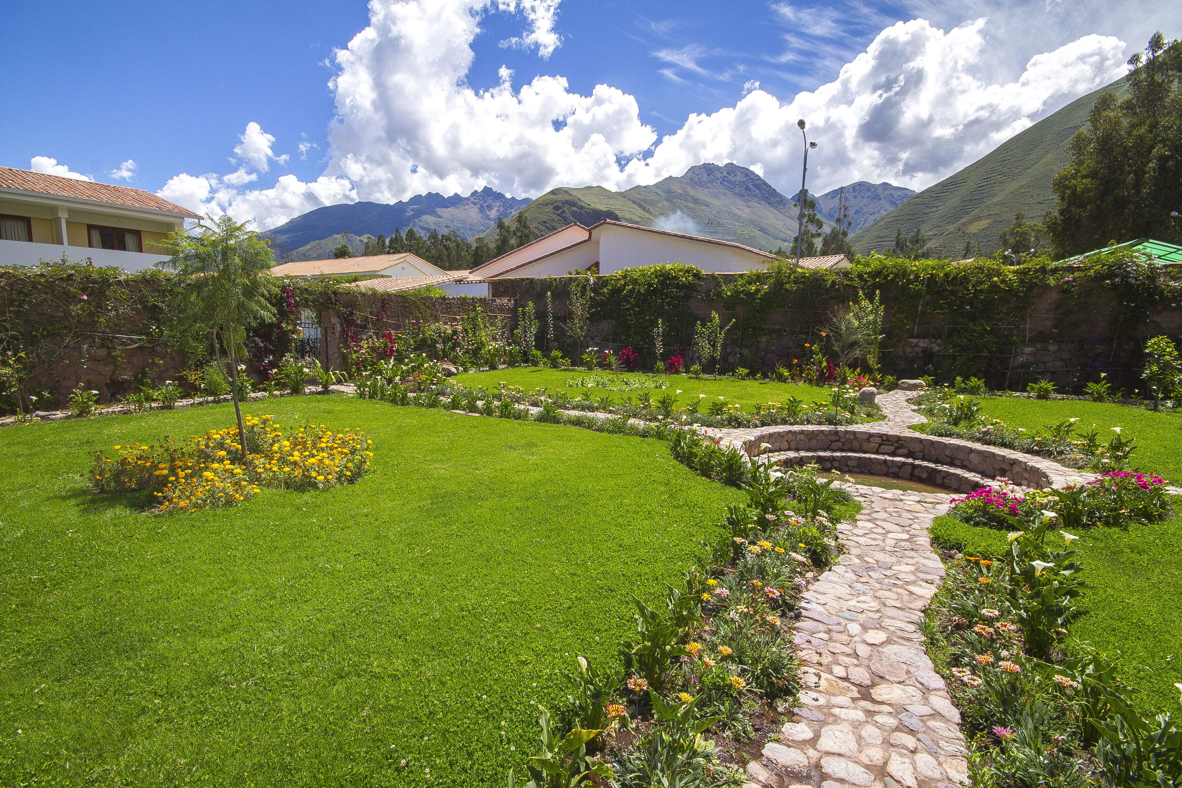 Un jardin bien entretenu, avec un chemin de pierres, une pelouse verdoyante et des plantes en fleurs.