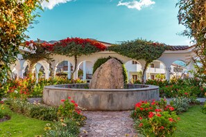 A courtyard with a central fountain, surrounded by arches and lush greenery. - Hotel Agustos Urubamba (Urubamba)