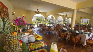 A buffet setup with various fruits, a pineapple centerpiece, and a fruit platter. - Hotel Agustos Urubamba (Urubamba)