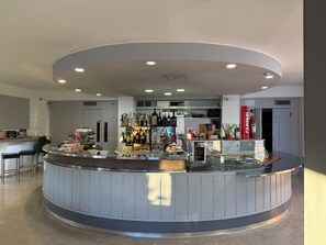 A modern bar area with a curved counter, stocked with various bottles and glasses, and a visible price tag. - Hotel Florida (Piove di Sacco)