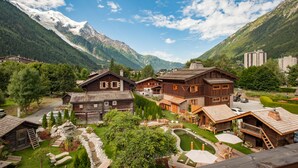 A mountain lodge with wooden architecture, a ski slope, and a view of snow-capped mountains. - Chalet Hôtel Hermitage - Hotel Chalet de Tradition (Chamonix-Mont-Blanc)