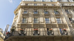 A multi-story hotel with ornate balconies, a prominent "HOTEL" sign, and decorative flower boxes. - Gardette Park Hotel (Paris)