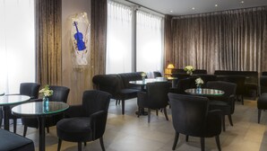A hotel lobby with a seating area, a piano, and a large window with curtains. - Gardette Park Hotel (Paris)
