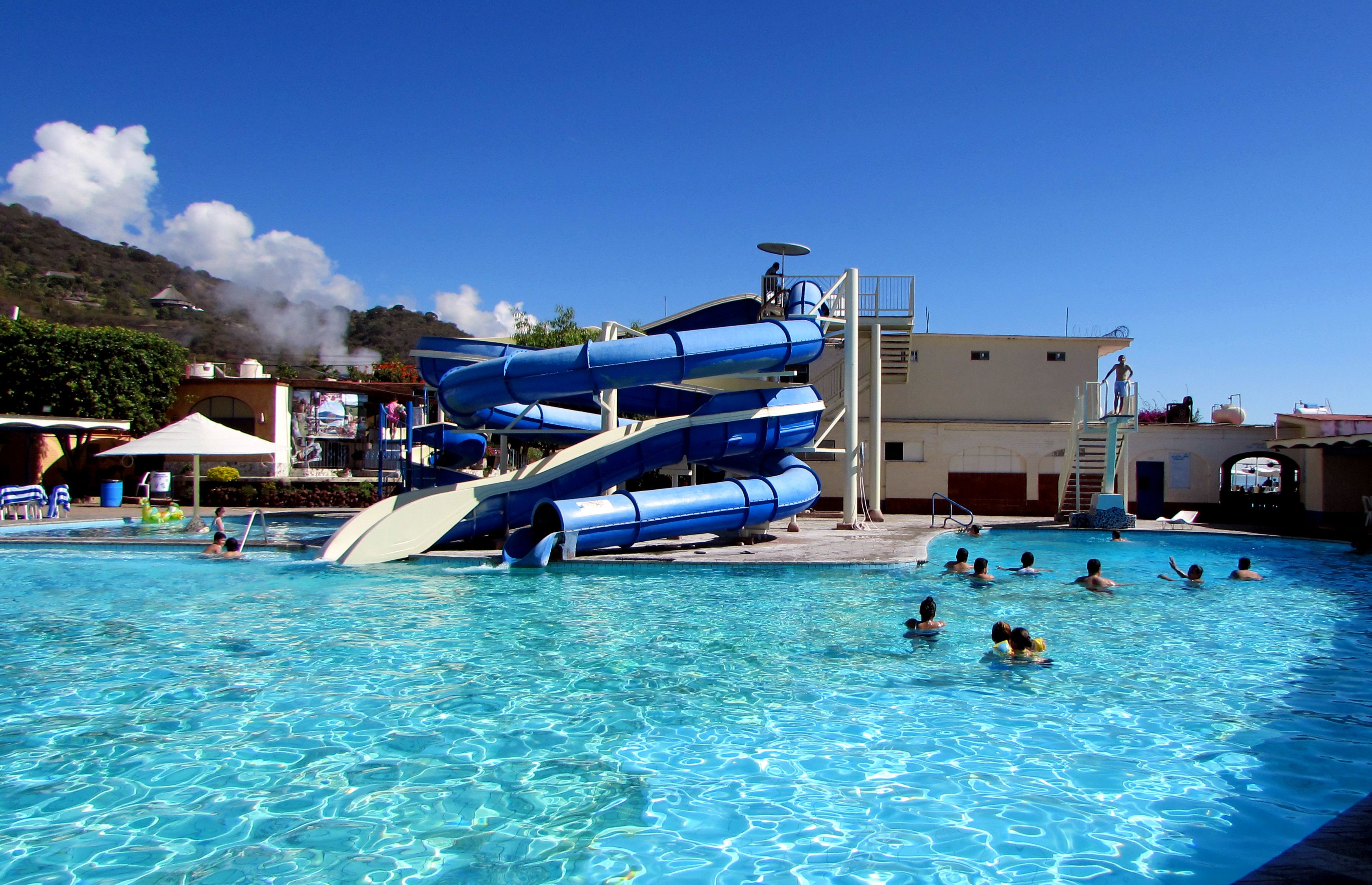 Une piscine avec un toboggan et un poste de surveillance pour les sauveteurs.