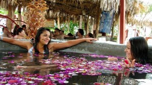 A communal water feature with people relaxing around it, surrounded by a thatched roof structure. - Hotel Balneario San Juan Cosalá (Jocotepec)