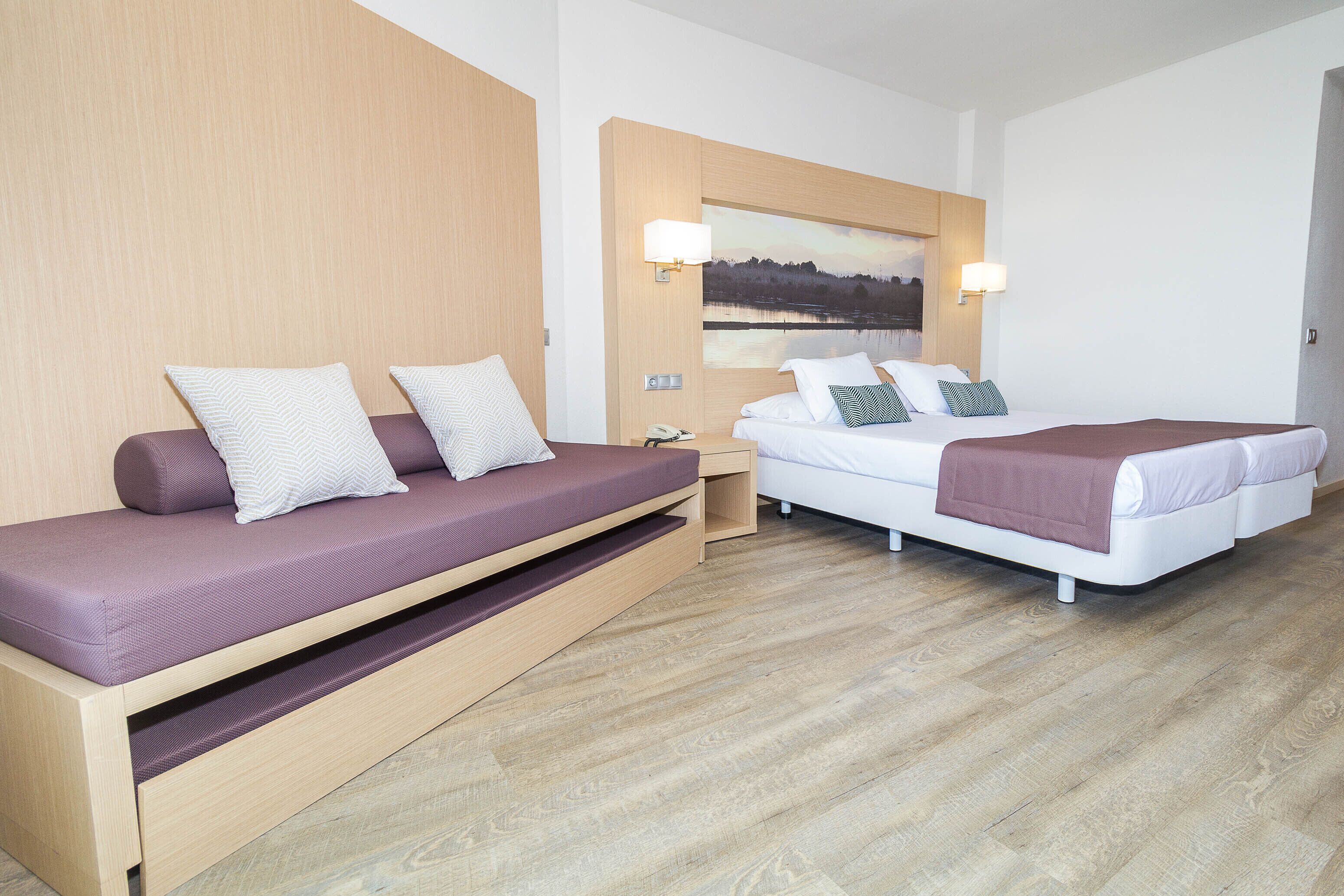 Una habitación de hotel moderna con sofá, cama y un cuadro en la pared.