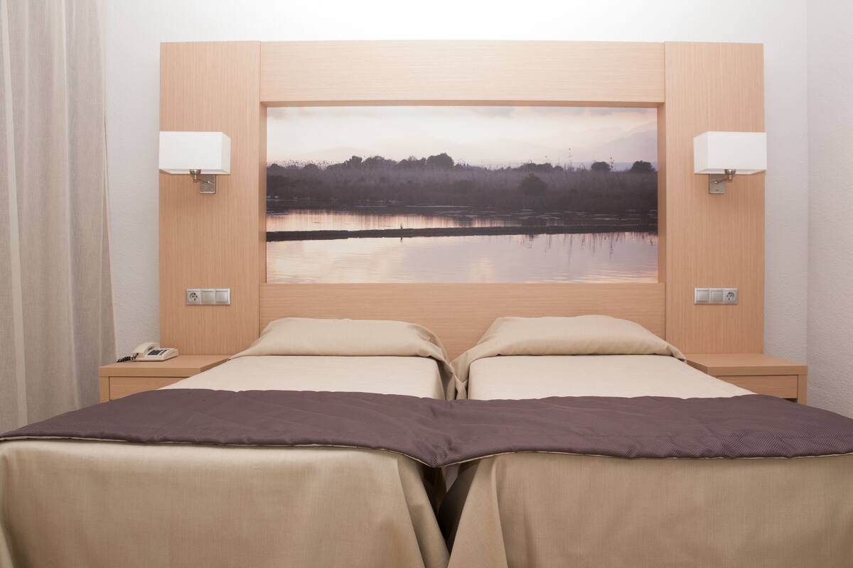 A double bed with two bedside tables, each with a lamp and a phone.
