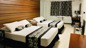 A hotel room with two beds, a desk, a chair, and a television. - Jupiter Suites (Makati)