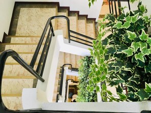 A staircase with a handrail and a potted plant beside it. - Jupiter Suites (Makati)