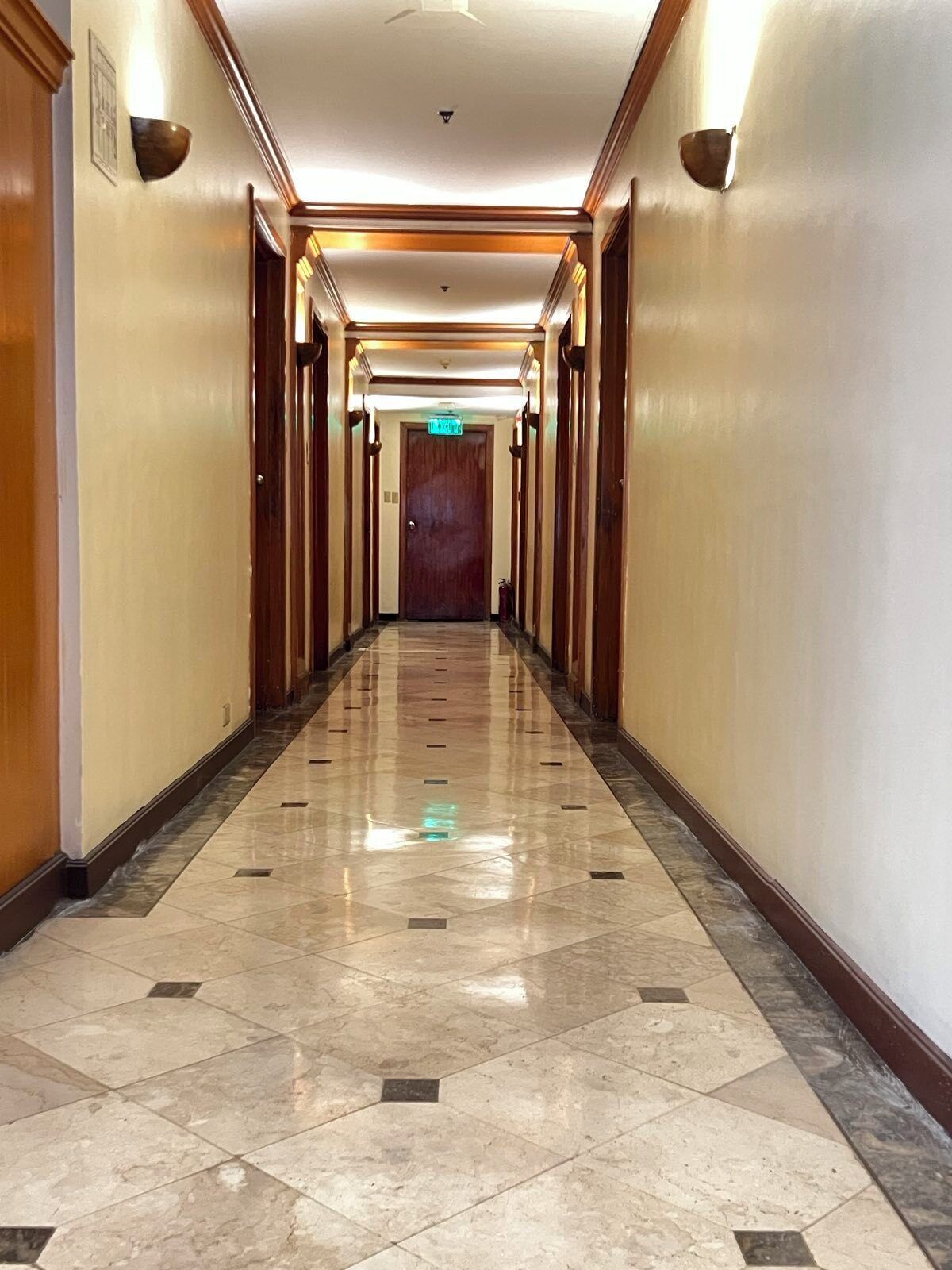 A long, well-lit hallway with a polished marble floor and wooden paneling on the walls.