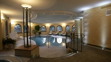 Een binnenzwembad, ligstoelen bij het zwembad