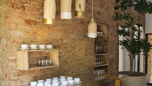 A rustic interior with exposed brick walls, wooden tables, hanging pendant lights, and shelves with glassware. - Alpine Attitude Boutique Hotel & Conference Venue (Pretoria)
