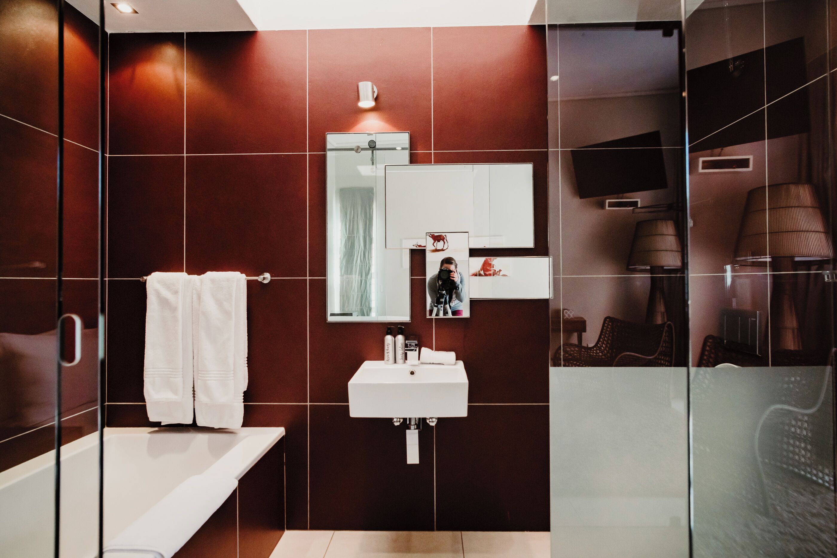 Une salle de bain moderne avec une douche à l’italienne en verre, un lavabo blanc et un grand miroir.
