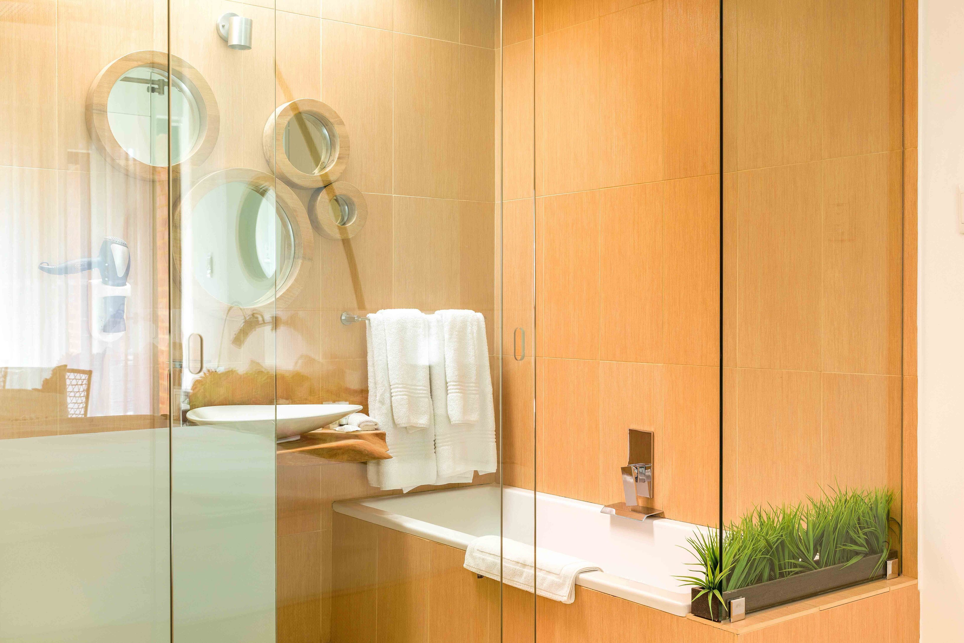 A modern bathroom with a glass shower enclosure, a white sink, and a mirror.