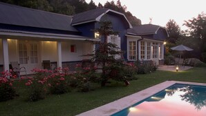 A house with a swimming pool, a covered patio, and a well-maintained garden with pink flowers. - Hosteria La Casa de Eugenia (San Martín de los Andes)
