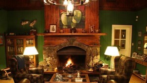 A cozy room with a stone fireplace, plaid armchairs, and a wooden coffee table. - Hosteria La Casa de Eugenia (San Martín de los Andes)