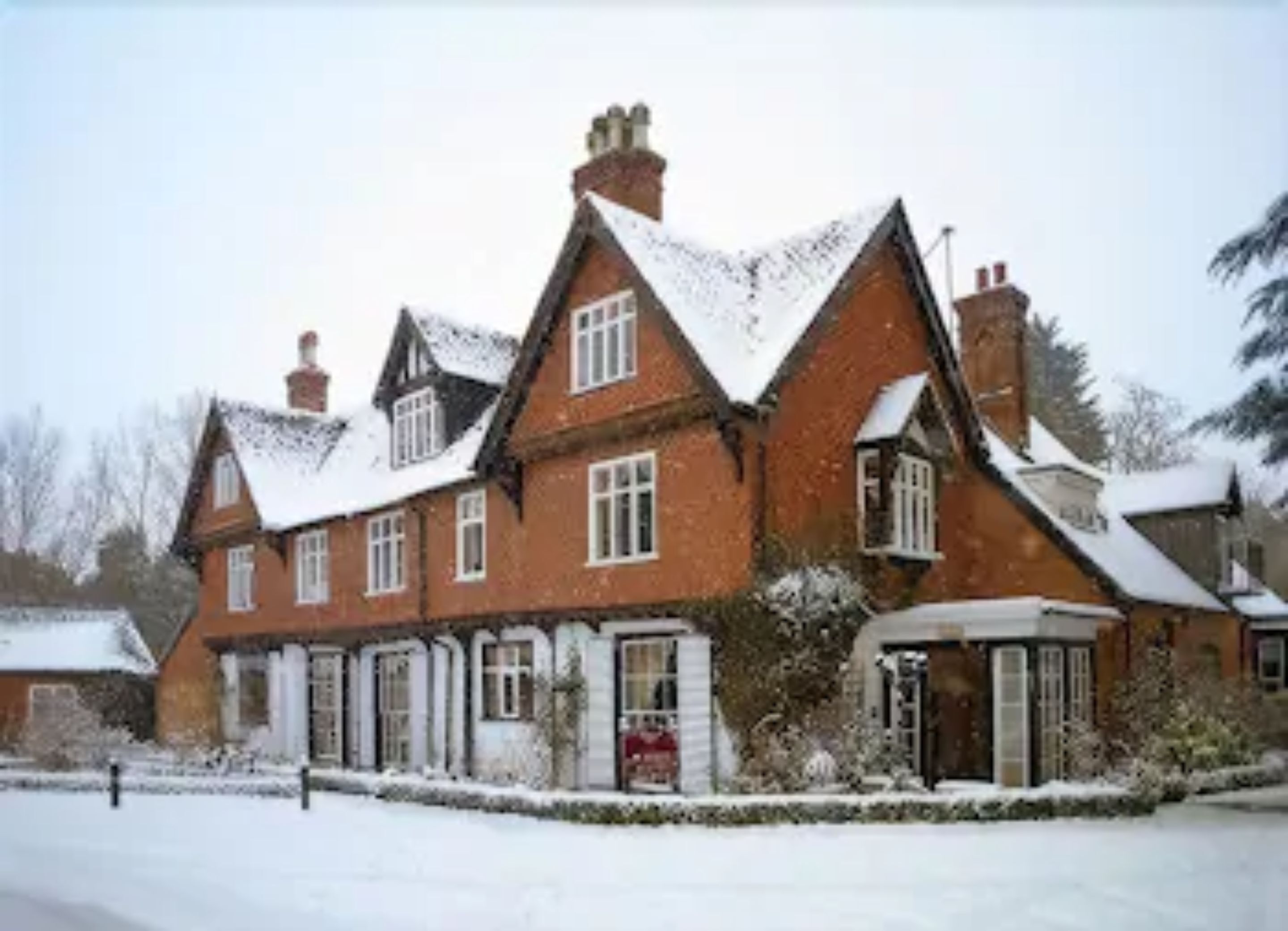 A traditional brick building with multiple chimneys and windows, surrounded by snow.