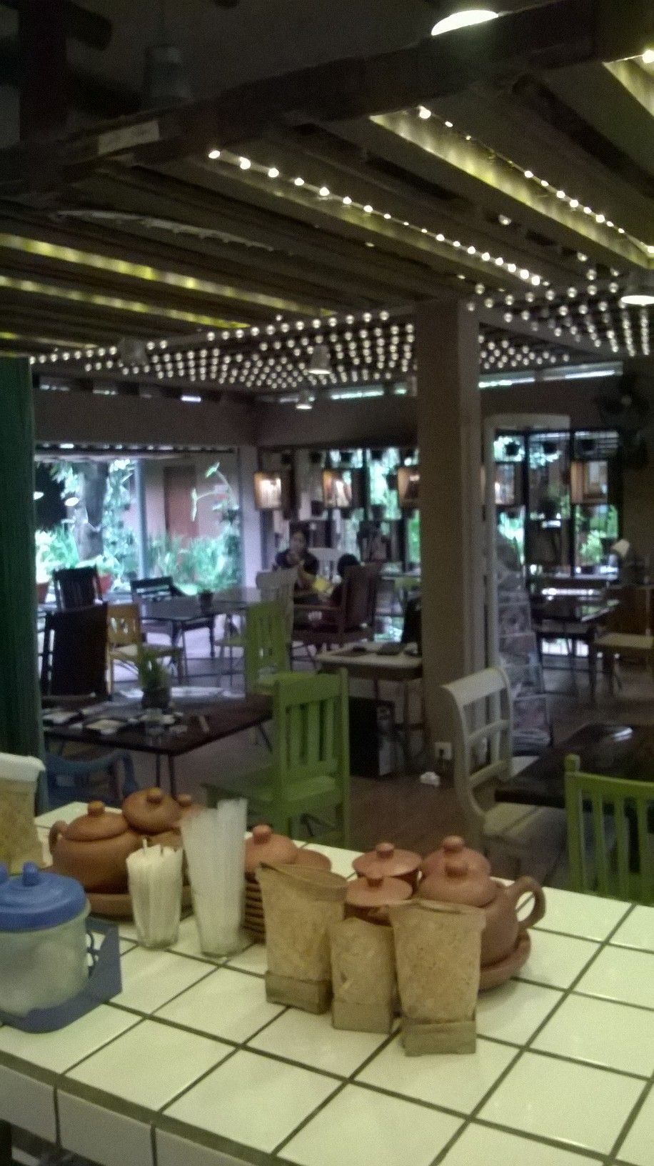 A restaurant interior with a tiled floor, tables with chairs, and a counter with food items.