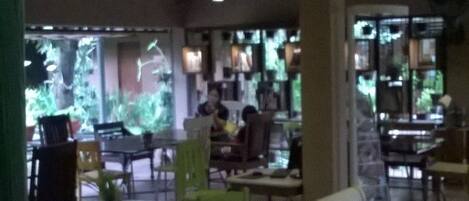 A restaurant interior with a tiled floor, tables with chairs, and a counter with food items.