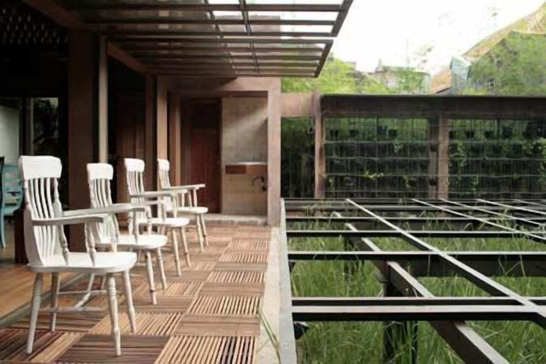 A covered outdoor seating area with wooden flooring and white chairs.