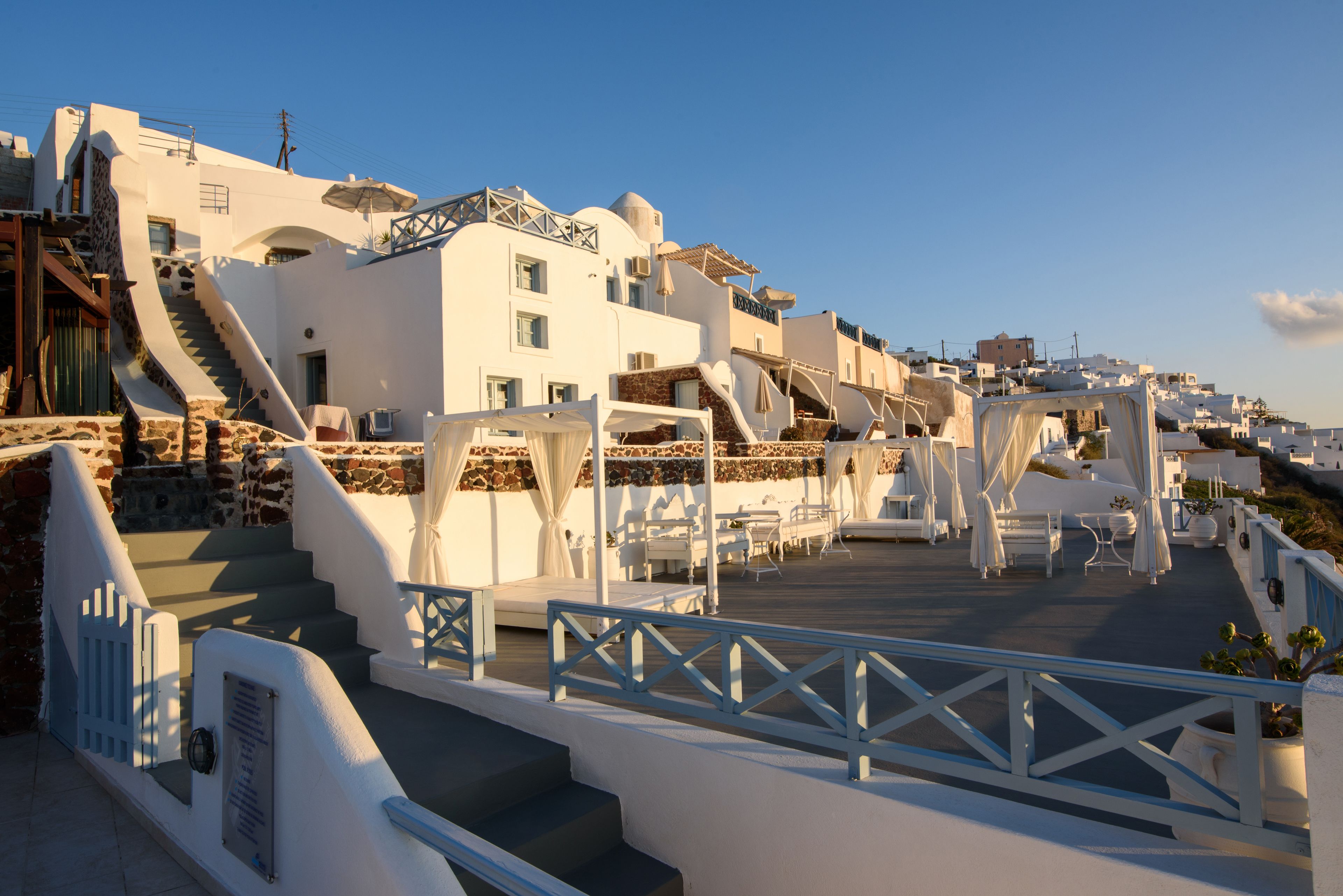 A coastal hotel with white buildings, a staircase leading to the upper floors, and outdoor seating areas.