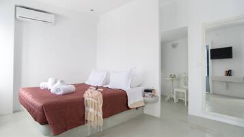 Una habitación de hotel moderna con una cama, un televisor, una mesita y un espejo.