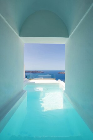 A clear view of a swimming pool with a view of the sea and distant land. - Ilioperato Hotel (Santorini)