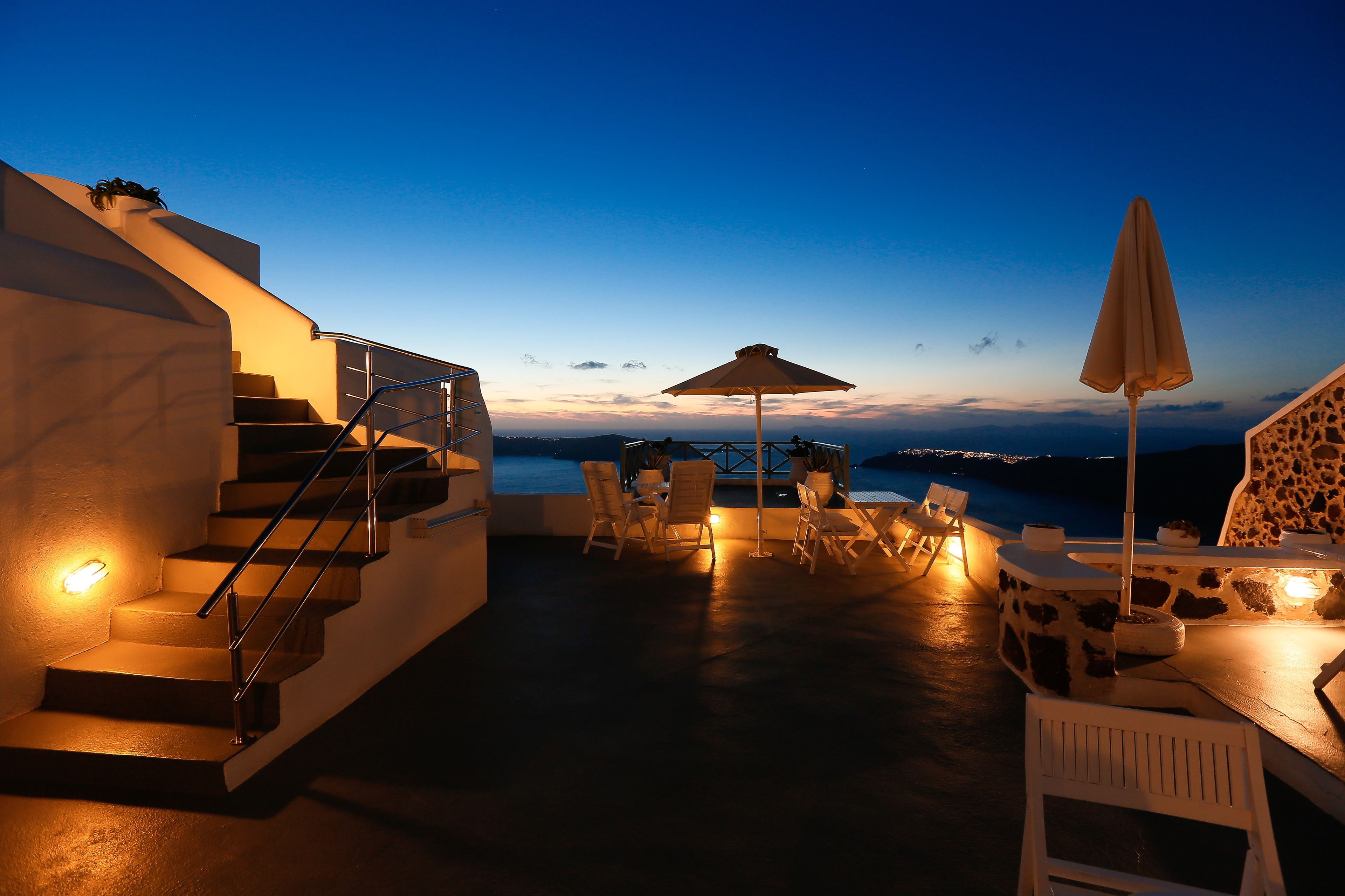 A terrace with a staircase, outdoor seating, and a view of the sea.