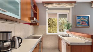Una cocina moderna con cafetera, ventana con persianas y una planta en maceta.