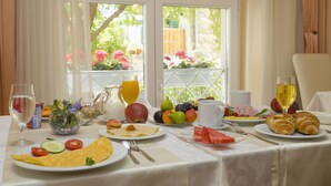 Una mesa de desayuno con diversos alimentos, un vaso de jugo de naranja y un vaso de vino blanco.