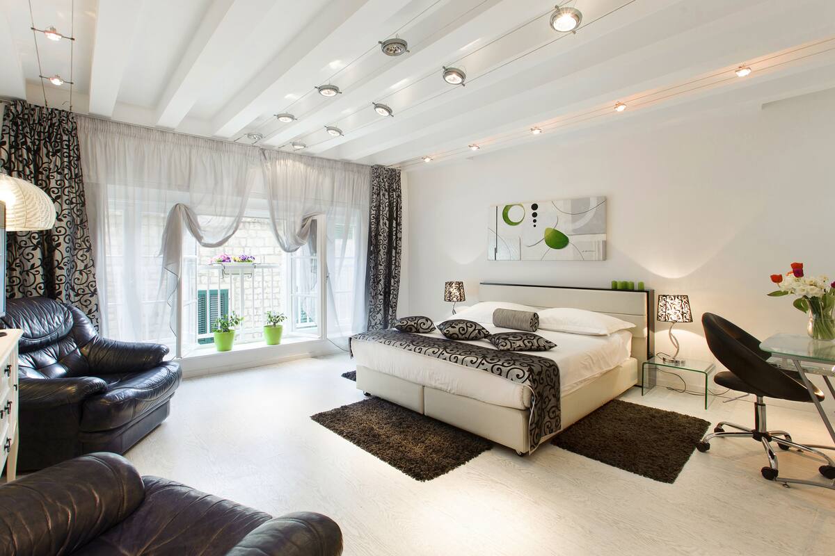 Une chambre moderne comprenant un lit, un canapé, un téléviseur et un bureau avec une chaise.