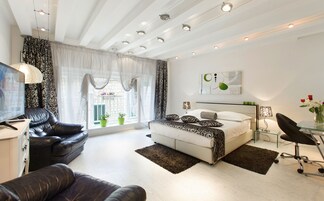 Un dormitorio moderno con cama, sofá, televisión y escritorio con silla.