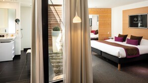 A modern hotel room with a bed, bedside table, and a large mirror. There is a staircase leading to an outdoor area.