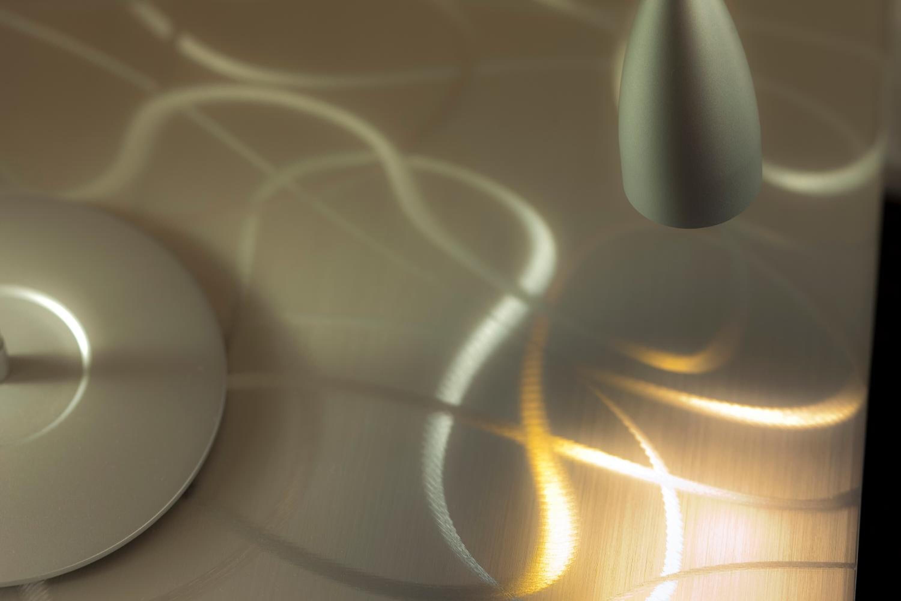 Primer plano de una estructura de techo metálica curva, con superficies reflectantes y juegos de luces.