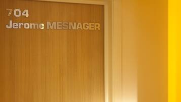 Una puerta de madera con el número 704 y el nombre 'Jerome MESNAGER' grabado.