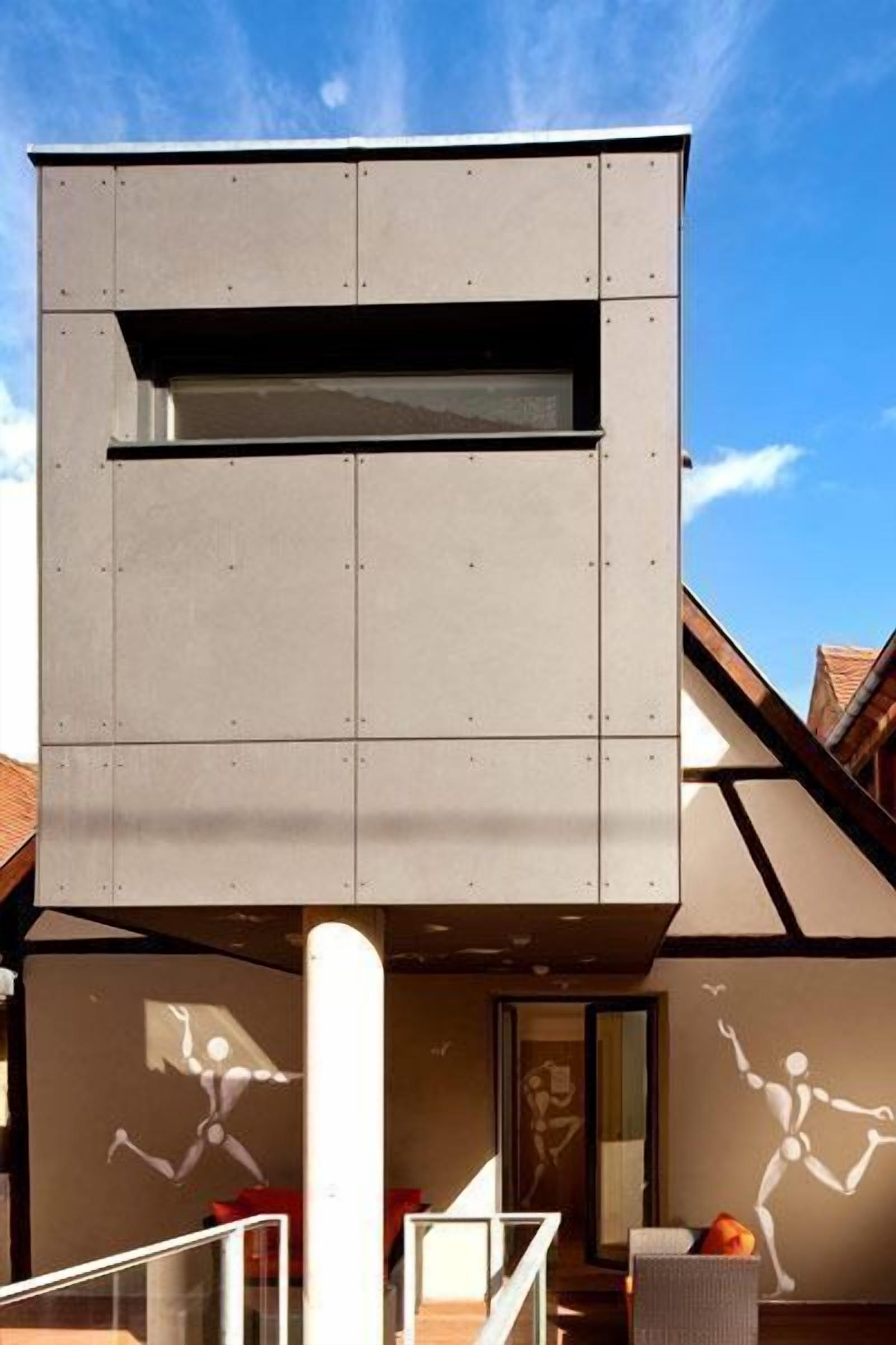 A modern building with a minimalist design, featuring a large window and a staircase leading to an upper level.