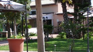 A courtyard with a palm tree, potted plants, and a tiled patio. - Villa Cristina (Syracuse)