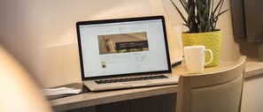 A laptop on a desk with a plant and a mug. - Hotel Carlton Mayfair (Düsseldorf)