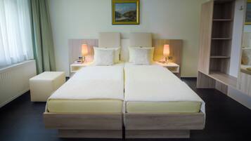 Uma cama de casal com duas mesas de cabeceira, cada uma com uma luminária, em um quarto de hotel.