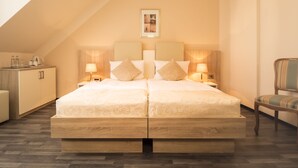 Una cama doble con estructura de madera, dos mesitas de noche con lámparas, una silla y un cuadro en la pared.