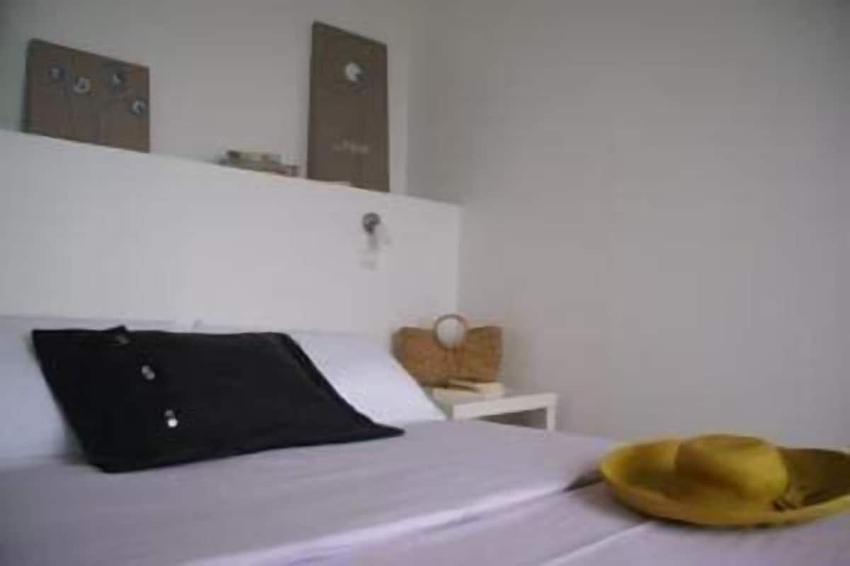 Un lit avec un oreiller noir et un chapeau jaune posé sur le côté.