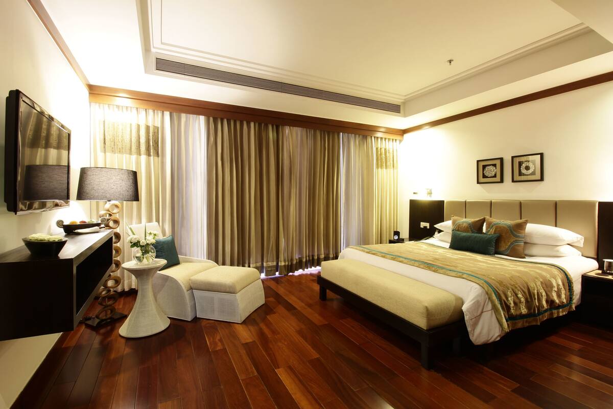 Habitación de hotel con una cama grande, un escritorio con lámpara, una silla y una pequeña mesa con flores.