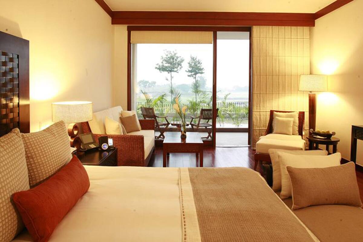 Habitación de hotel con una cama grande, dos sofás, una mesita y vistas al exterior.