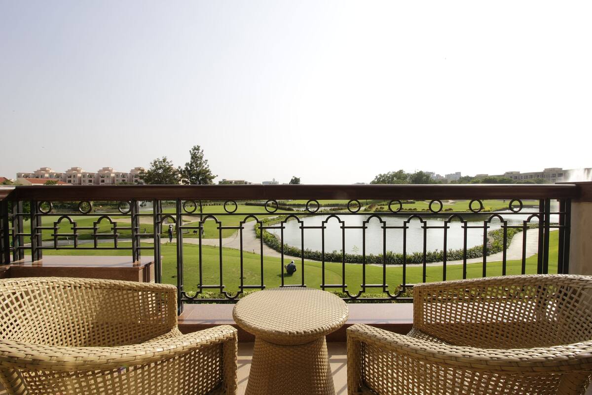 Un balcón con mobiliario de mimbre y vistas a un campo de golf y al agua.