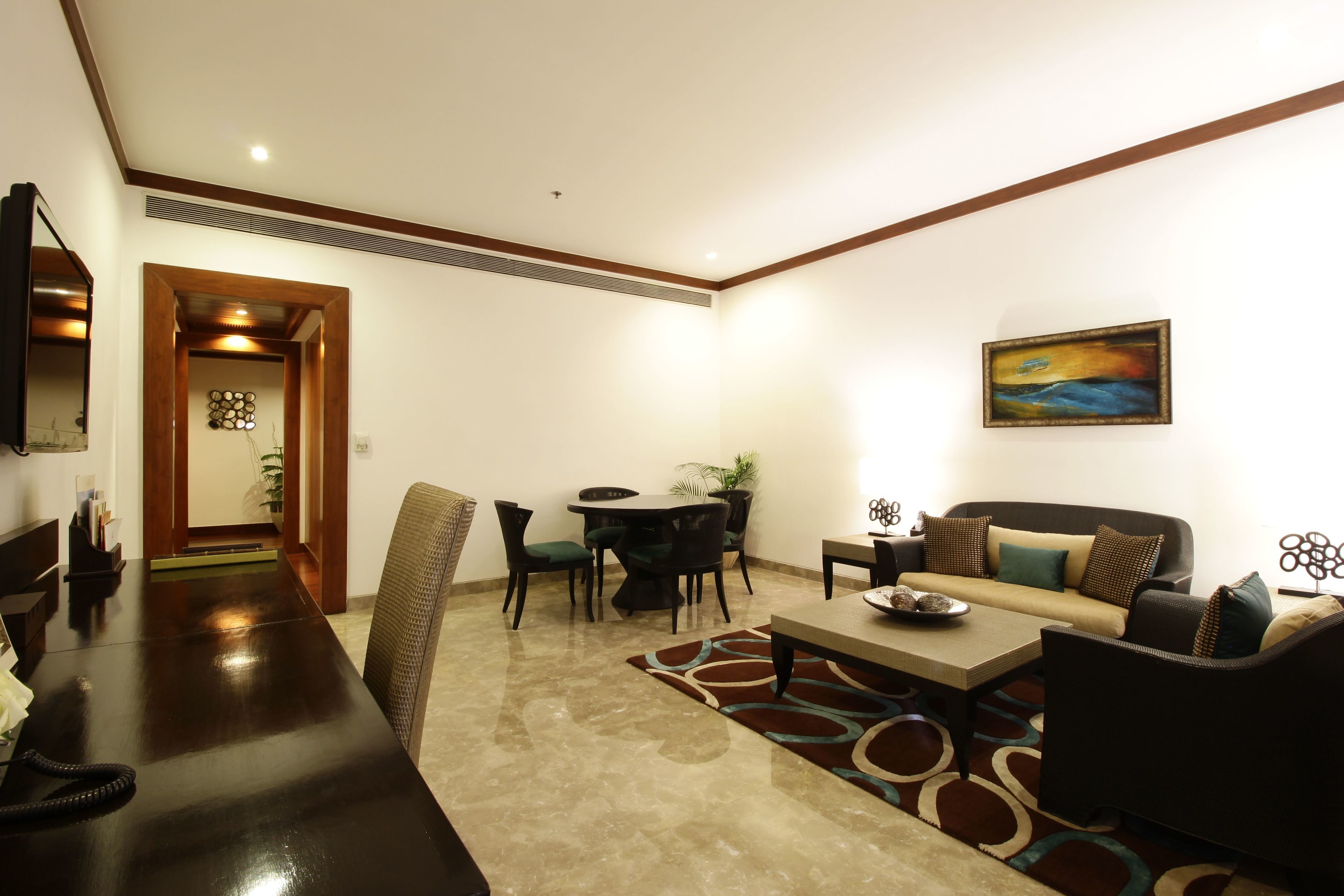 Una sala de estar moderna con comedor, un conjunto de sofás, una mesa de centro y un cuadro en la pared.