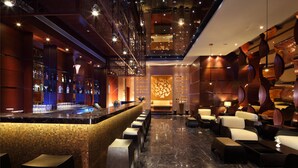 A bar area with a long counter, bar stools, and a seating area with couches and tables. - Jaypee Greens Golf & Spa Resort (Greater Noida)