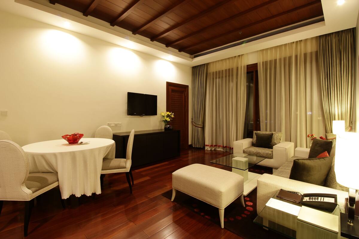 Una sala de estar moderna con techo de madera, televisor de pantalla plana, zona de comedor con mesa redonda y un conjunto de sofás.