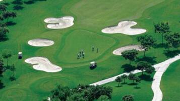 Un campo de golf con búnkeres de arena, árboles y un sendero sinuoso.