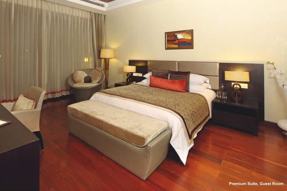 Habitación de hotel con una cama grande, un escritorio, una silla, una mesita de noche y un cuadro en la pared.
